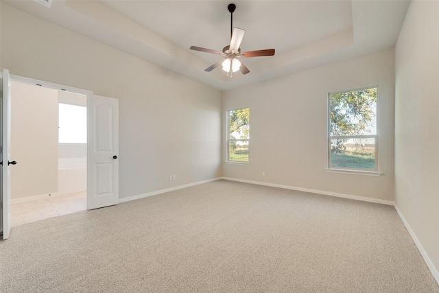 carpeted empty room featuring a raised ceiling and ceiling fan