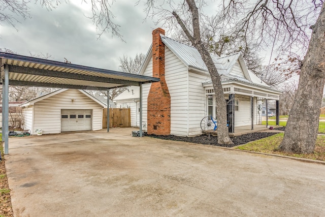 view of property exterior featuring a carport, an outdoor structure, a garage, and a porch