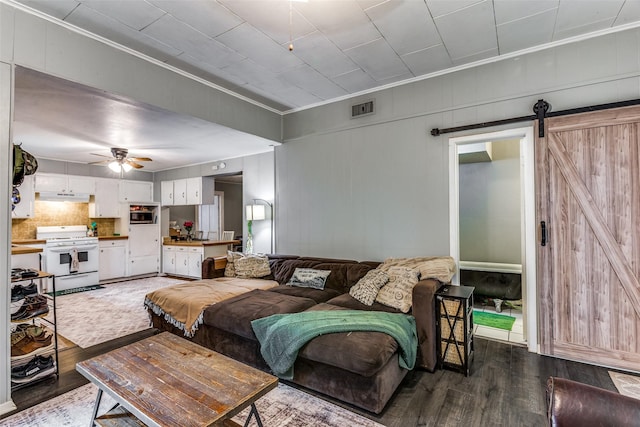 living room with crown molding, a barn door, hardwood / wood-style floors, and ceiling fan