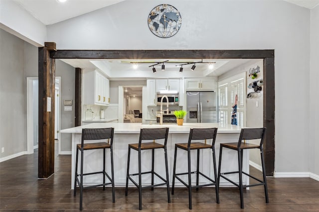 kitchen with dark hardwood / wood-style floors, appliances with stainless steel finishes, white cabinets, and a breakfast bar