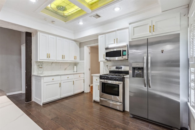 kitchen with decorative backsplash, white cabinetry, appliances with stainless steel finishes, and dark hardwood / wood-style flooring