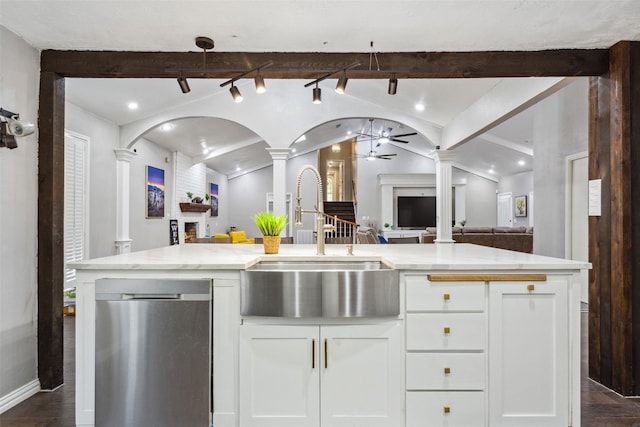 kitchen featuring white cabinetry, ceiling fan, vaulted ceiling with beams, stainless steel dishwasher, and sink