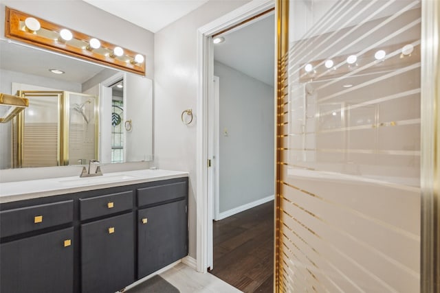 bathroom featuring hardwood / wood-style floors, walk in shower, and vanity