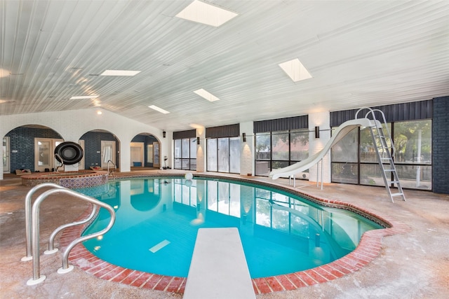 view of swimming pool featuring a skylight, a diving board, and a water slide