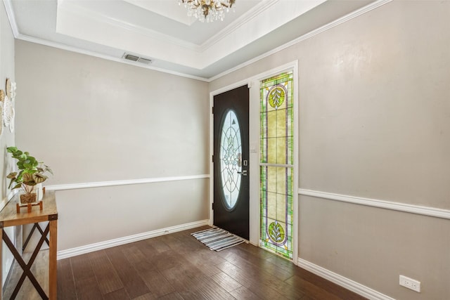 foyer with a chandelier, ornamental molding, dark hardwood / wood-style floors, and a tray ceiling