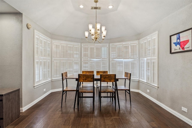 dining area with dark wood-type flooring and an inviting chandelier