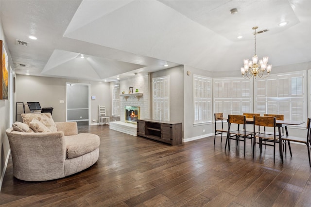 living room with dark hardwood / wood-style floors, a raised ceiling, a notable chandelier, and a fireplace