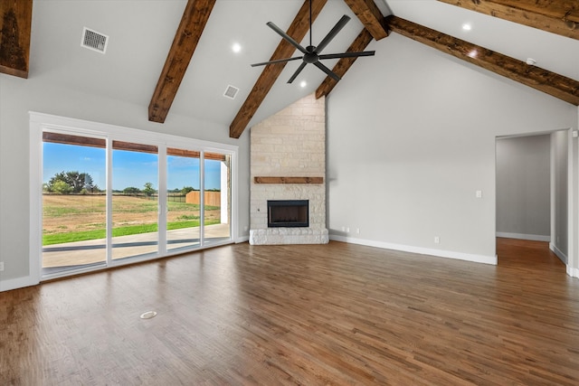 unfurnished living room with hardwood / wood-style floors, high vaulted ceiling, and a stone fireplace