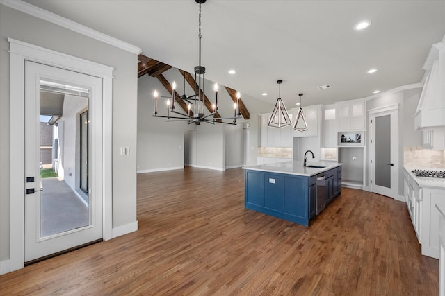 kitchen featuring sink, decorative light fixtures, light wood-type flooring, tasteful backsplash, and white cabinetry