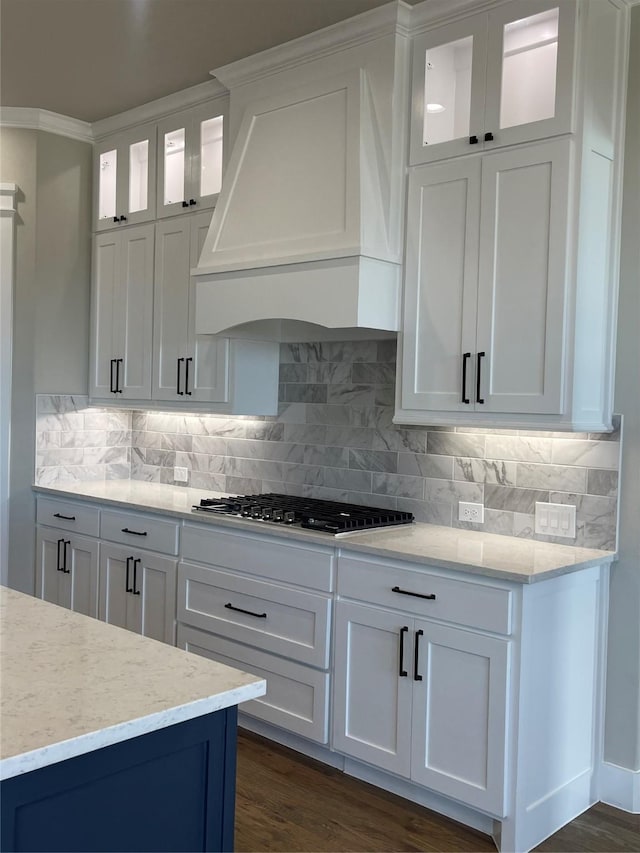 kitchen featuring tasteful backsplash, stainless steel gas stovetop, custom exhaust hood, and white cabinets