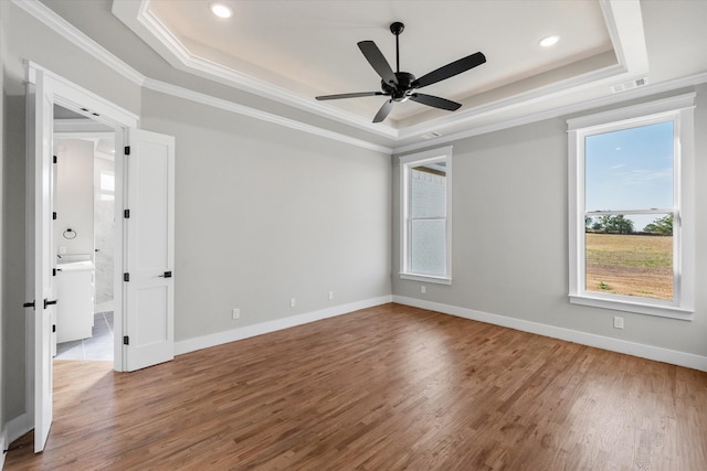 unfurnished room with a tray ceiling, ceiling fan, ornamental molding, and wood-type flooring