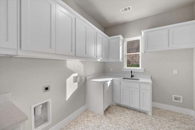 washroom featuring sink, electric dryer hookup, light tile patterned floors, and cabinets