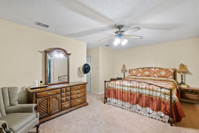 bedroom with a textured ceiling, light colored carpet, and ceiling fan