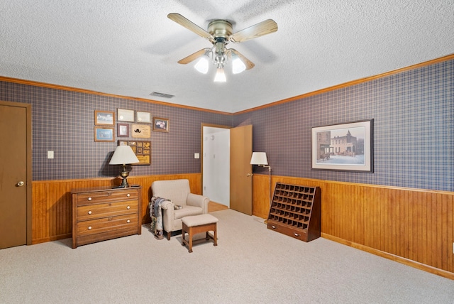 sitting room with wood walls, a textured ceiling, light colored carpet, and ceiling fan