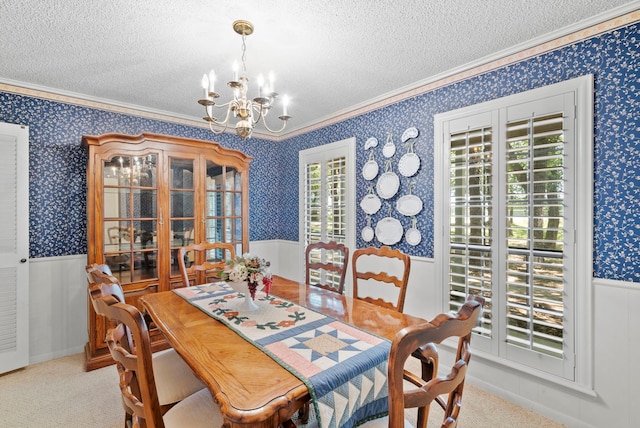 dining room with ornamental molding, light carpet, a textured ceiling, and an inviting chandelier