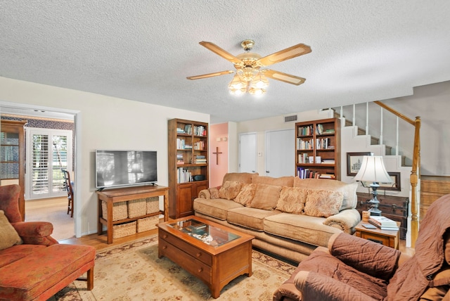 carpeted living room with a textured ceiling and ceiling fan