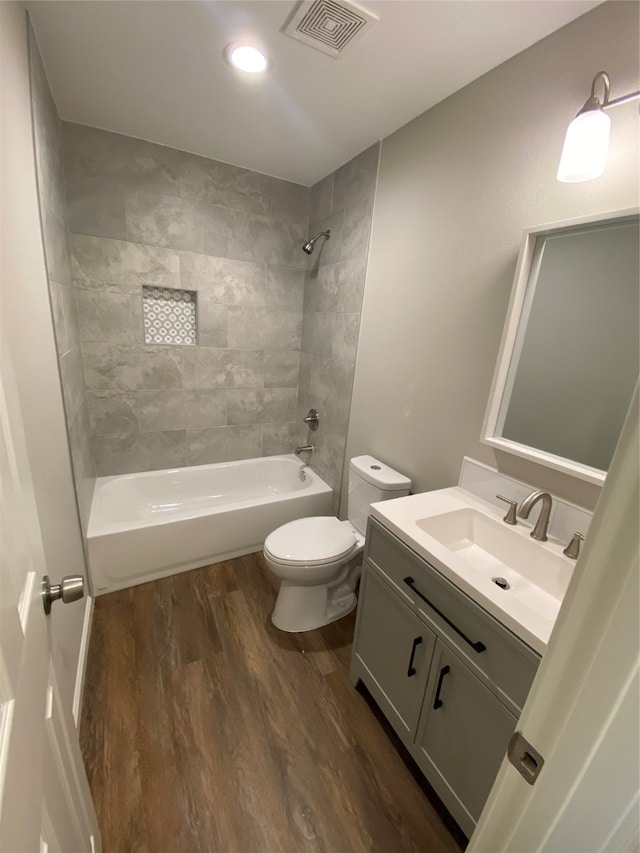 full bathroom featuring hardwood / wood-style floors, vanity, toilet, and tiled shower / bath