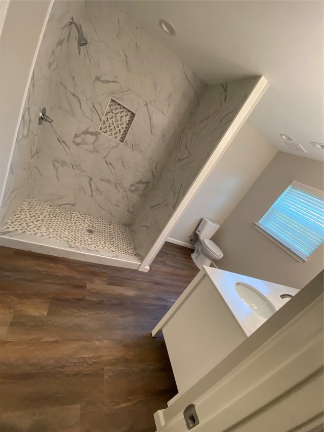 room details with a tile shower, vanity, and wood-type flooring