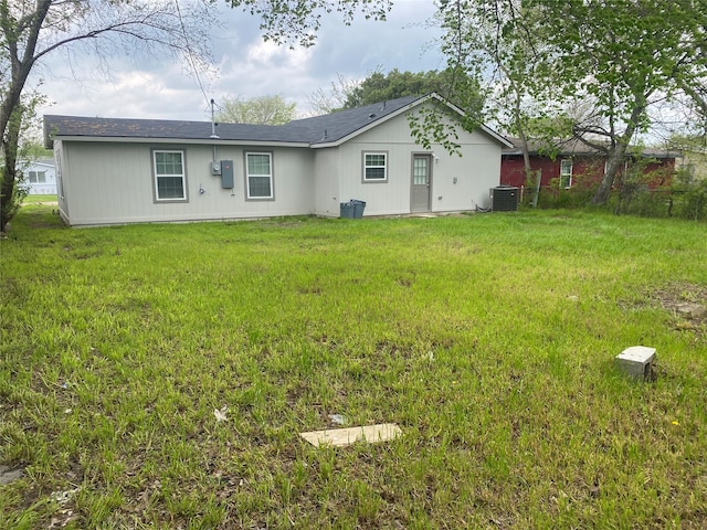 rear view of property featuring a lawn and central AC