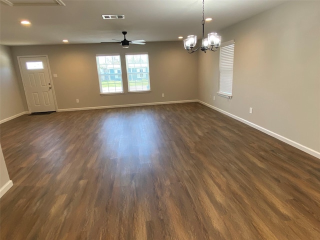 spare room with ceiling fan with notable chandelier and dark hardwood / wood-style floors