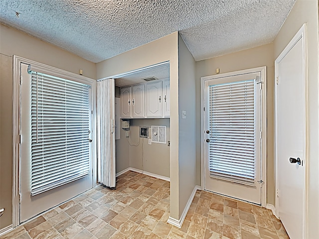 doorway featuring stone finish flooring, baseboards, and a textured ceiling