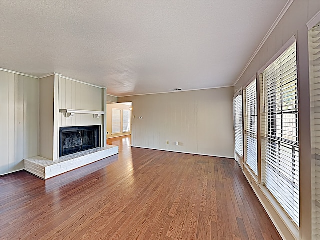 unfurnished living room featuring a fireplace, a textured ceiling, crown molding, and hardwood / wood-style floors