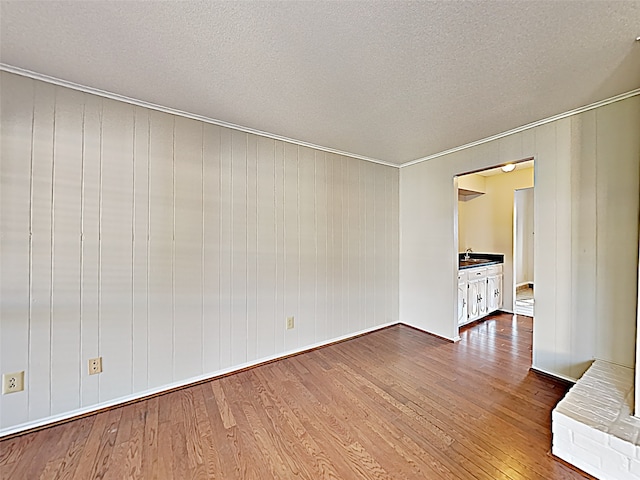 unfurnished room featuring a textured ceiling, a sink, and wood finished floors