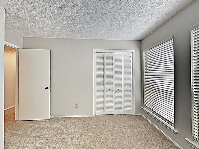 unfurnished bedroom with light carpet, a closet, and a textured ceiling