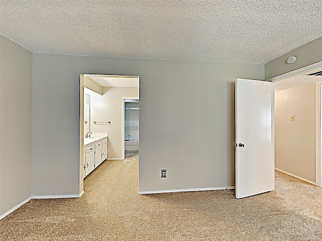 unfurnished bedroom featuring sink, light carpet, and a textured ceiling