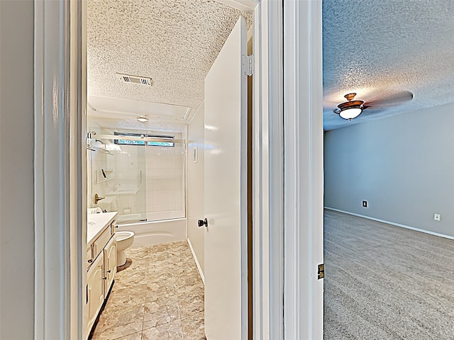 full bathroom with vanity, a textured ceiling, tiled shower / bath combo, and toilet