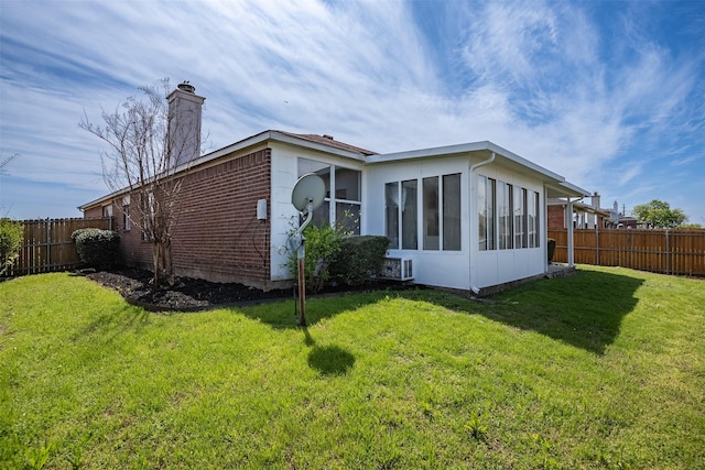 back of property featuring a sunroom and a lawn