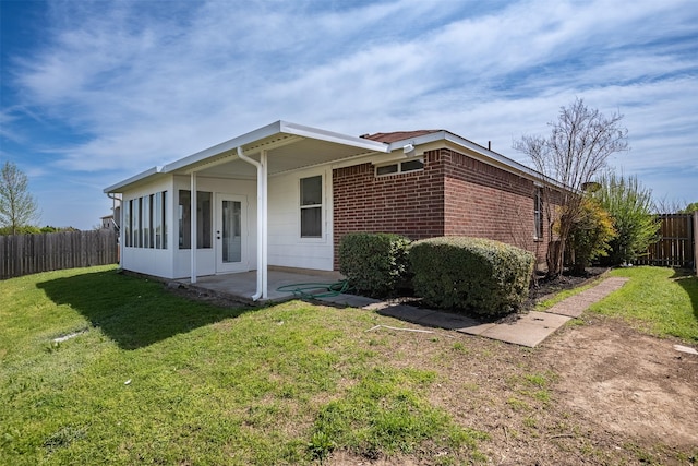 view of property exterior featuring a lawn, a patio, and a sunroom