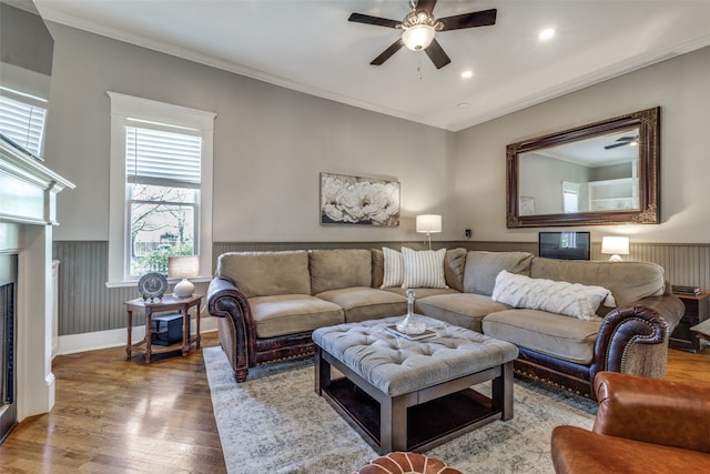 living room with a fireplace, ornamental molding, hardwood / wood-style floors, and ceiling fan