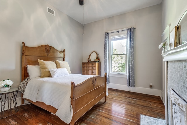 bedroom featuring a fireplace, ceiling fan, and dark hardwood / wood-style floors