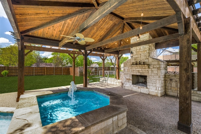 view of pool with a yard, an outdoor stone fireplace, a patio, and ceiling fan