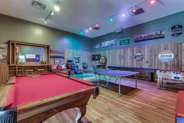 rec room featuring track lighting, hardwood / wood-style floors, wooden walls, pool table, and indoor bar