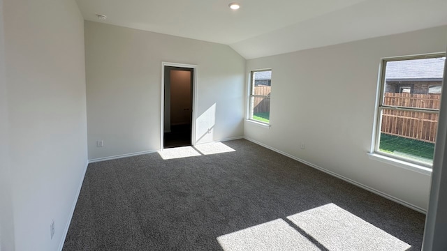 unfurnished bedroom with lofted ceiling and dark carpet