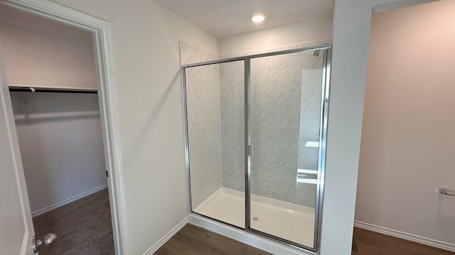 bathroom featuring a shower with shower door and wood-type flooring