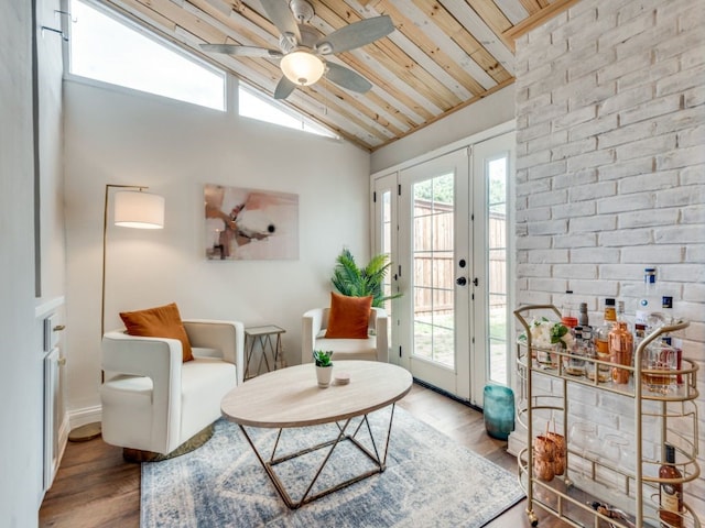 living area featuring hardwood / wood-style flooring, ceiling fan, brick wall, lofted ceiling, and wood ceiling