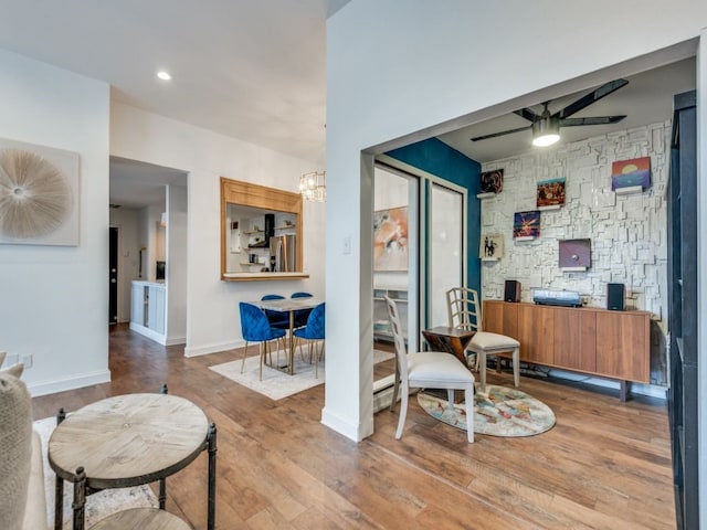 sitting room featuring ceiling fan with notable chandelier and hardwood / wood-style floors