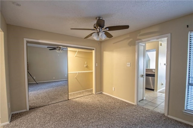 unfurnished bedroom with light carpet, a closet, a textured ceiling, and ceiling fan