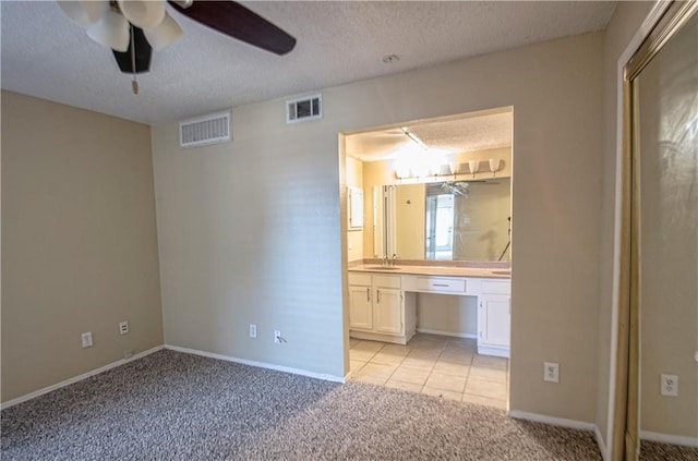 unfurnished bedroom featuring a textured ceiling, light colored carpet, sink, and ceiling fan