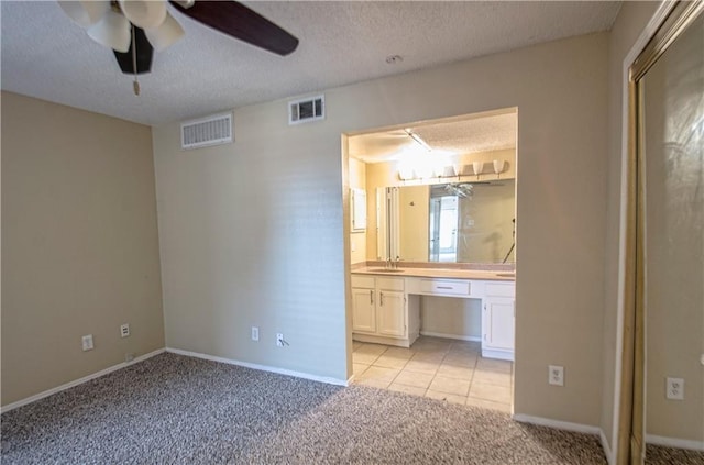 unfurnished bedroom featuring sink, light carpet, a textured ceiling, and ensuite bath