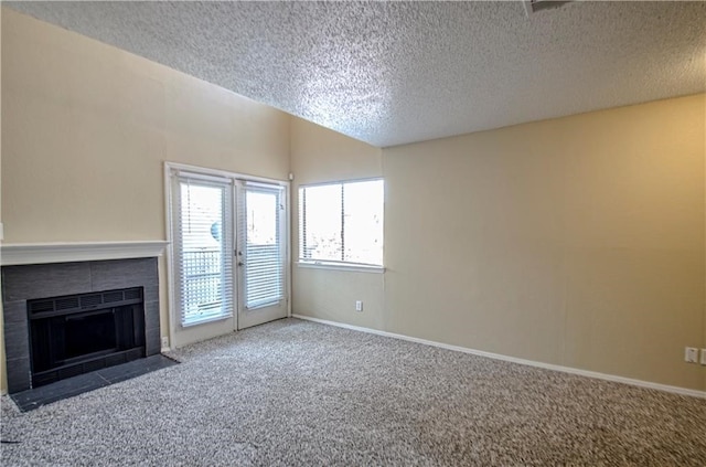 unfurnished living room with carpet floors, a textured ceiling, and a tile fireplace