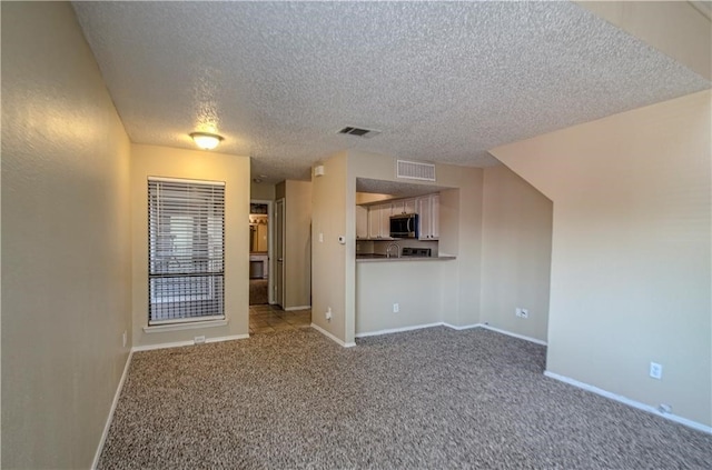 unfurnished living room featuring carpet floors and a textured ceiling