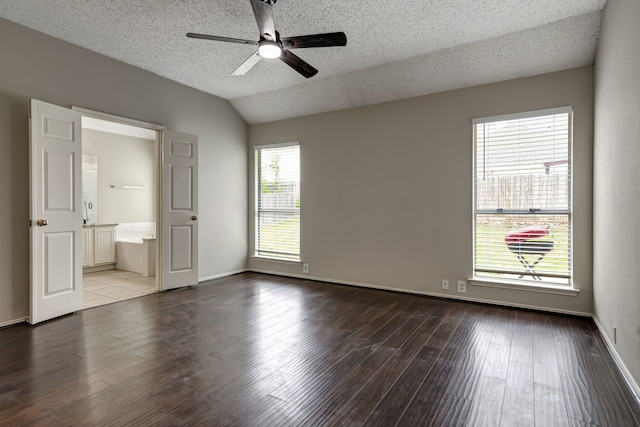 unfurnished bedroom featuring vaulted ceiling, hardwood / wood-style floors, ensuite bath, ceiling fan, and a textured ceiling