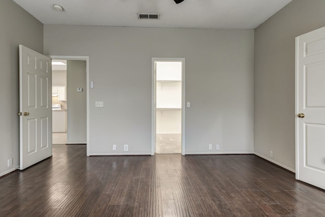 unfurnished bedroom with a walk in closet and dark hardwood / wood-style flooring