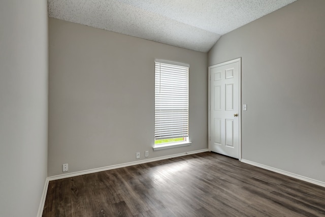 empty room with vaulted ceiling, dark hardwood / wood-style floors, and a textured ceiling