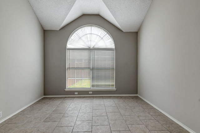 unfurnished room featuring lofted ceiling, a textured ceiling, and light tile patterned floors