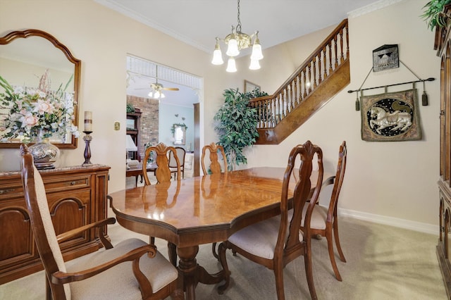 dining space featuring crown molding, brick wall, carpet, and ceiling fan with notable chandelier